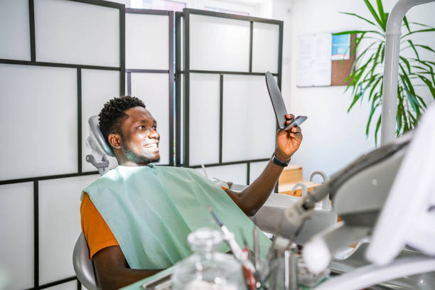 a dental patient checking his teeth with a handheld mirror