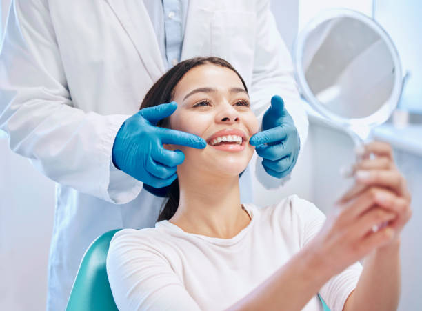 image of a patient looking at her teeth happily while the dentist is behind her