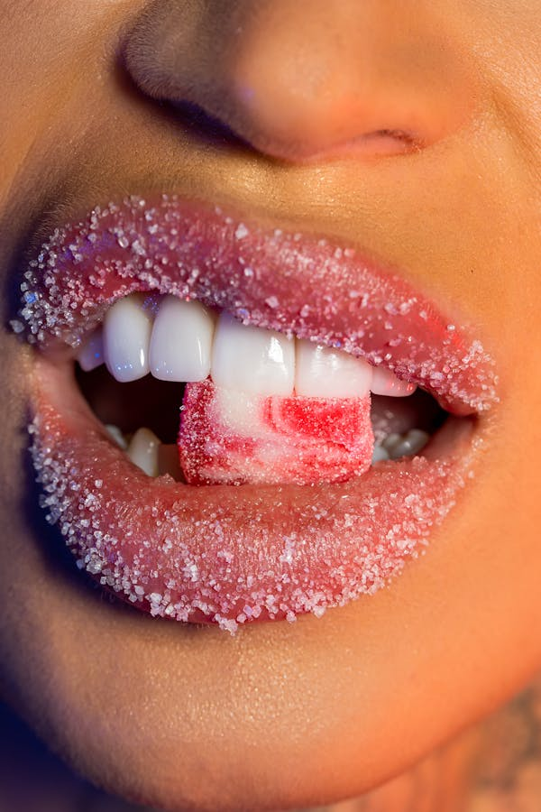 close-up on a person's teeth biting on a sugary candy