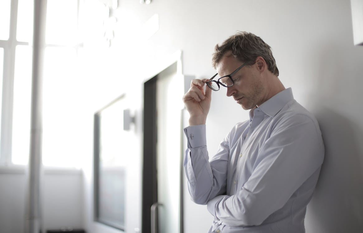 a man leaning on the wall looking stressed