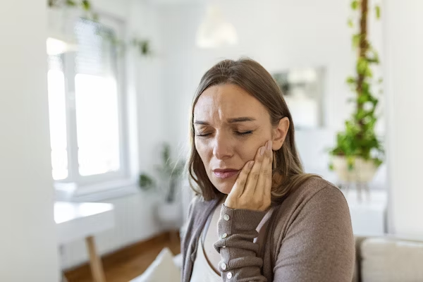 a woman touching her jaw due to tooth pain
