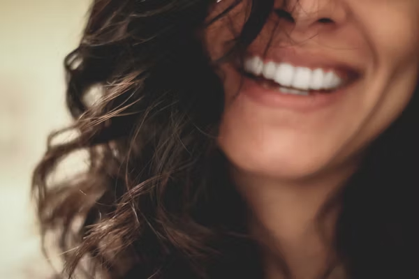 a blurry image of a woman smiling widely showing her teeth
