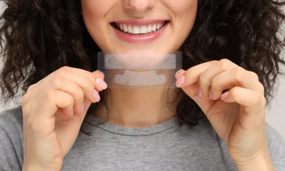 person holding teeth whitening strips in front of smile Charlotte NC