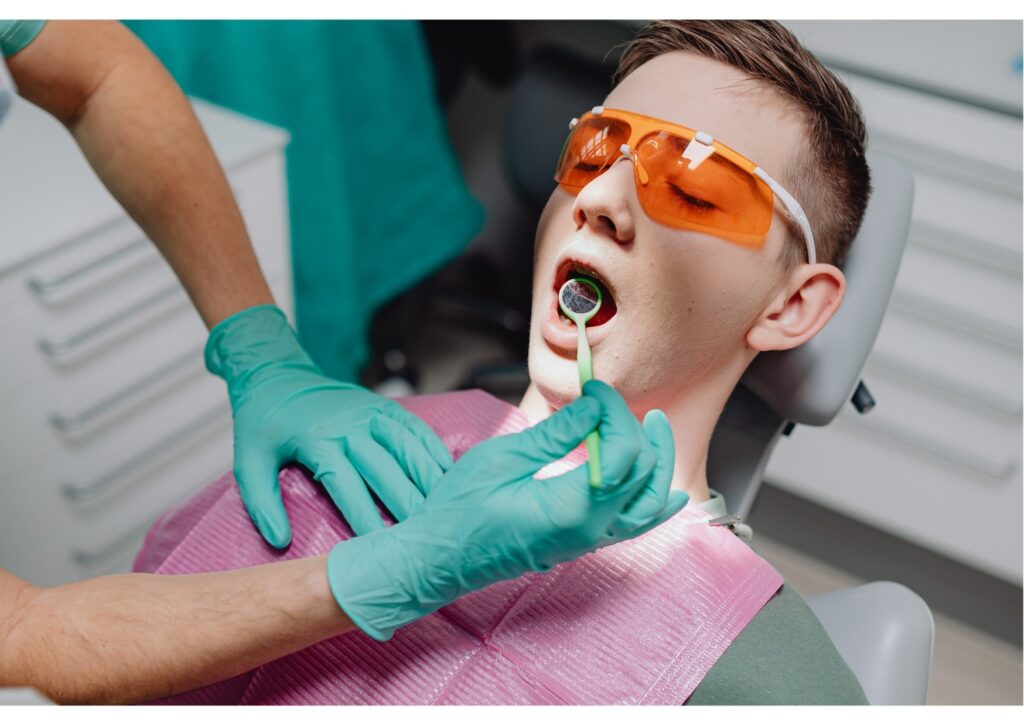 Patient undergoing dental exam with protective glasses while dentist checks teeth, part of evaluating cost of dental implants.