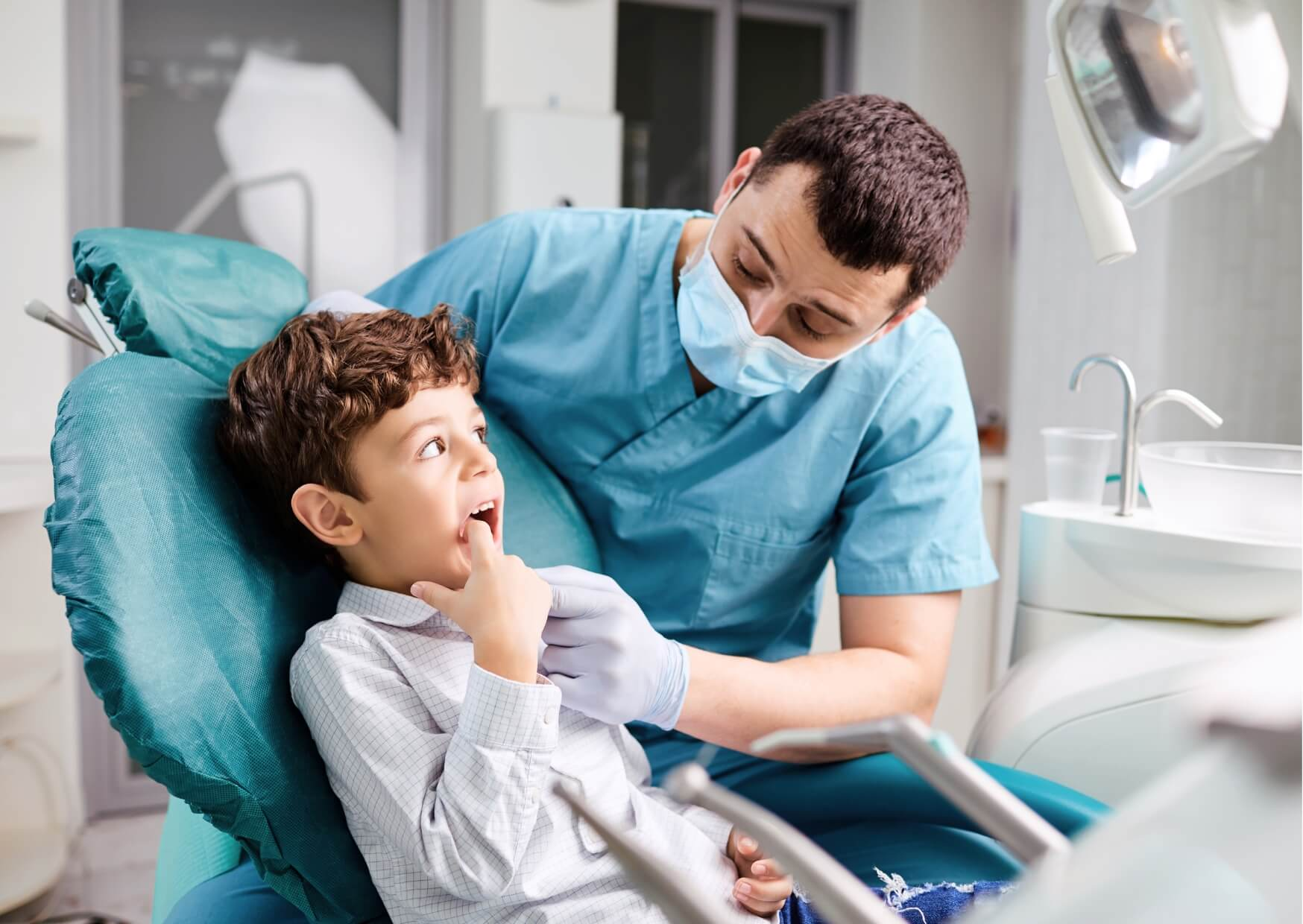 Pediatric dentist examining a child's teeth and explaining the need for kids dental spacers during a routine dental visit.