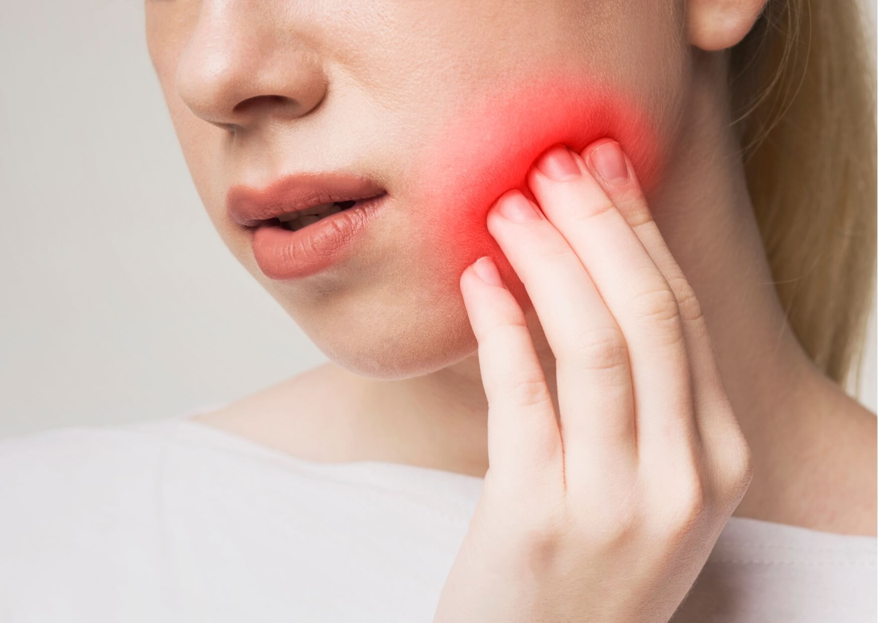 Person holding their jaw due to tooth pain, illustrating common symptoms and the need for toothache relief.