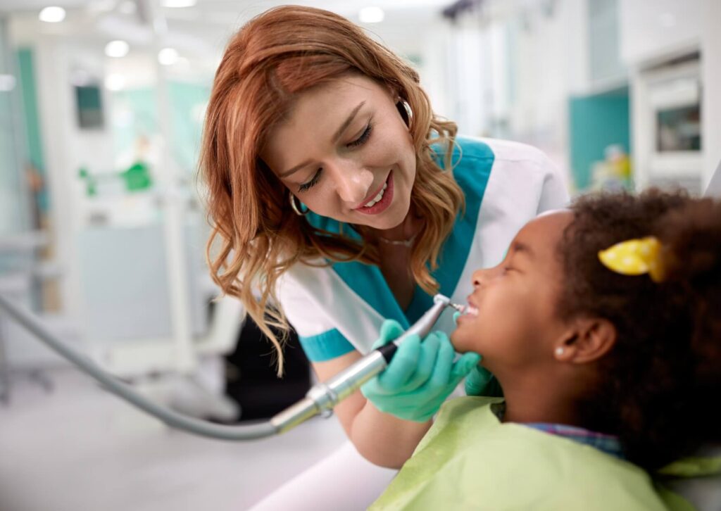 Dentist performing a gentle dental checkup for a young child during an early preventive dental visit.