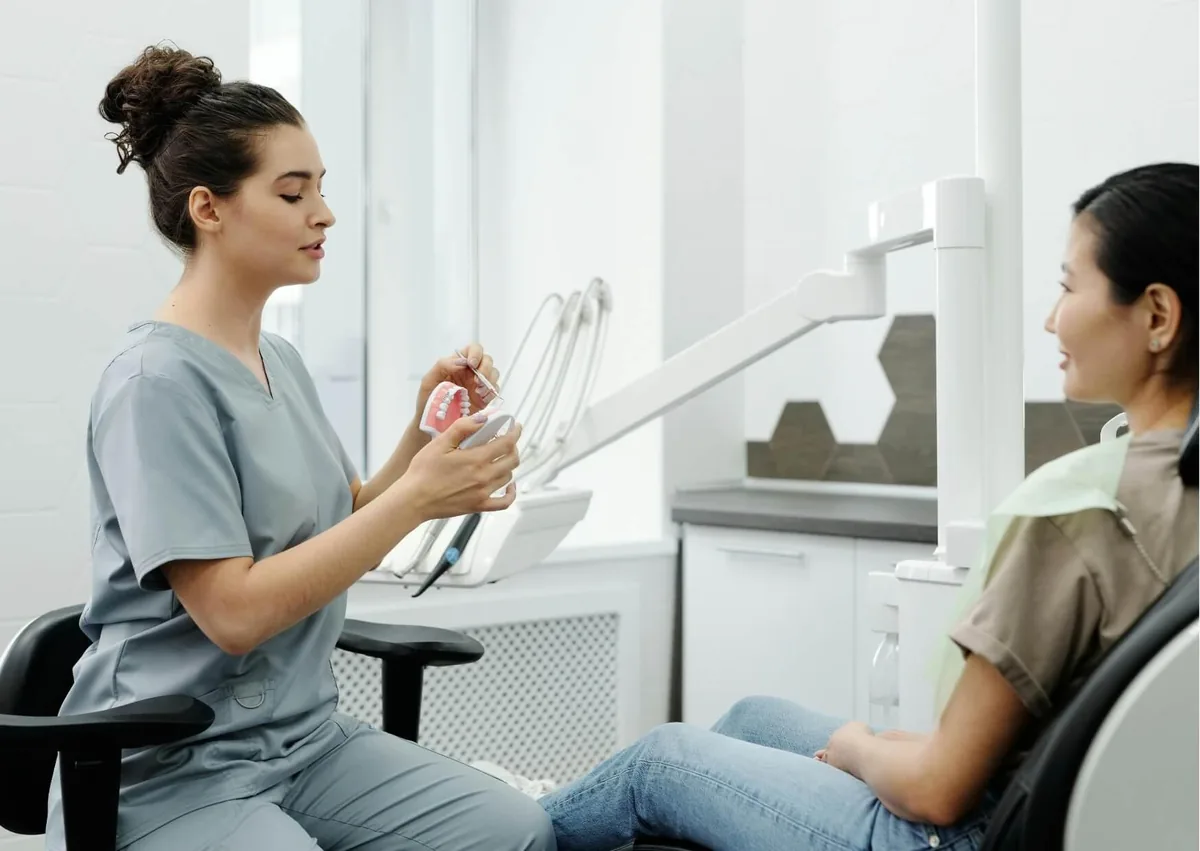 Dental professional discussing gummy smile treatment options with a patient using a teeth model.