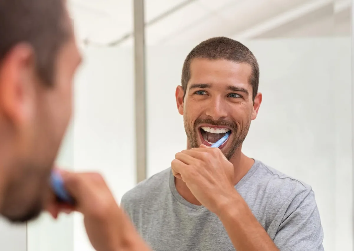 Man brushing his teeth to remove plaque and help prevent cavities from forming.