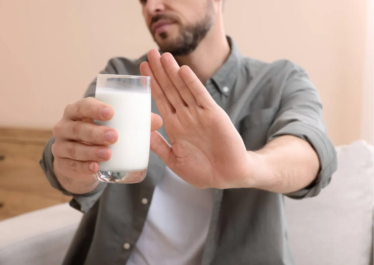 Man avoiding a glass of milk while following dietary restrictions after dental implant surgery.