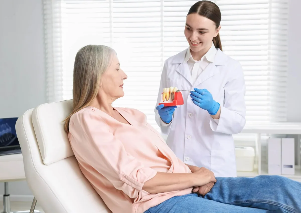 Dental professional discussing affordable dental implants with a patient using a tooth implant model.